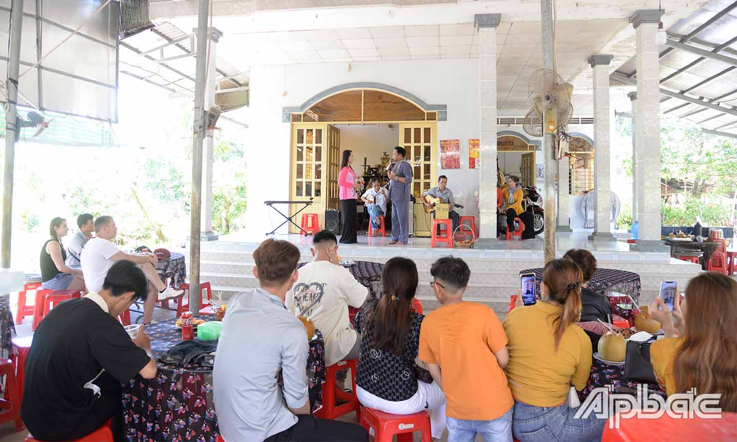 Tourists watch a performance of traditional music at Tan Phong Islet, Cai Lay District.