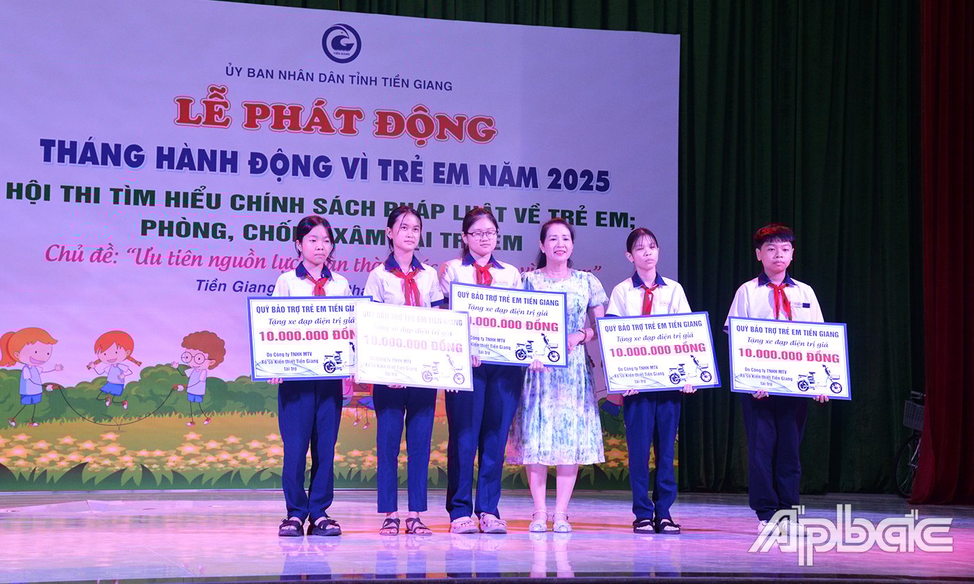 Đại diện Công ty TNHH MTV Xổ số kiến thiết Tiền Giang trao bảng tượng trưng xe đạp điện cho 5 học sinh