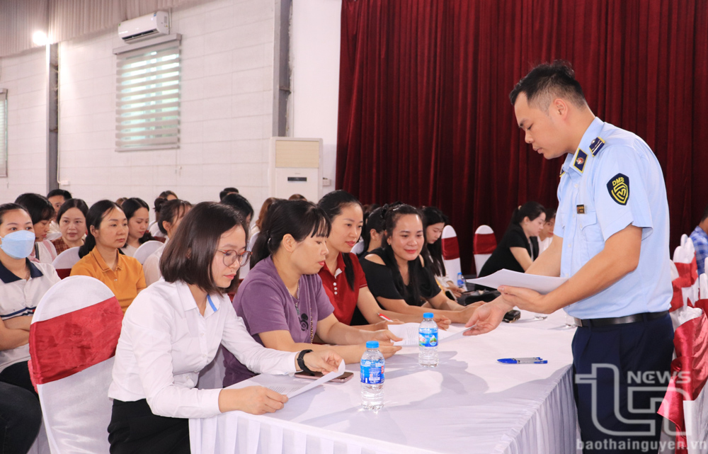 Cán bộ Đội Quản lý thị trường số 3 cho các đại biểu ký cam kết tại buổi tuyên truyền.