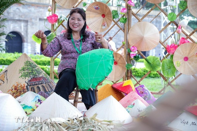 Nghệ nhân Tạ Thu Hương trực tiếp làm nón lá tại Lễ hội Du lịch Hà Nội 2025. (Ảnh: Khánh Hòa/TTXVN)