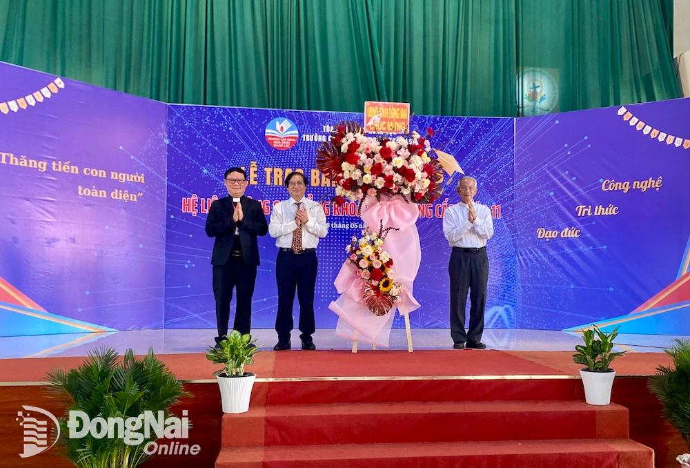 Đại diện Hội đồng quản trị và Ban giám hiệu Trường cao đẳng Hòa Bình Xuân Lộc nhận lẵng hoa của UBND tỉnh do Phó chủ tịch UBND tỉnh Nguyễn Sơn Hùng trao tặng. Ảnh: Hải Yến