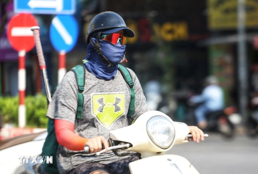 Người dân ra đường ngày nắng nóng thường bịt kín để đảm bảo sức khỏe. Ảnh: TTXVN