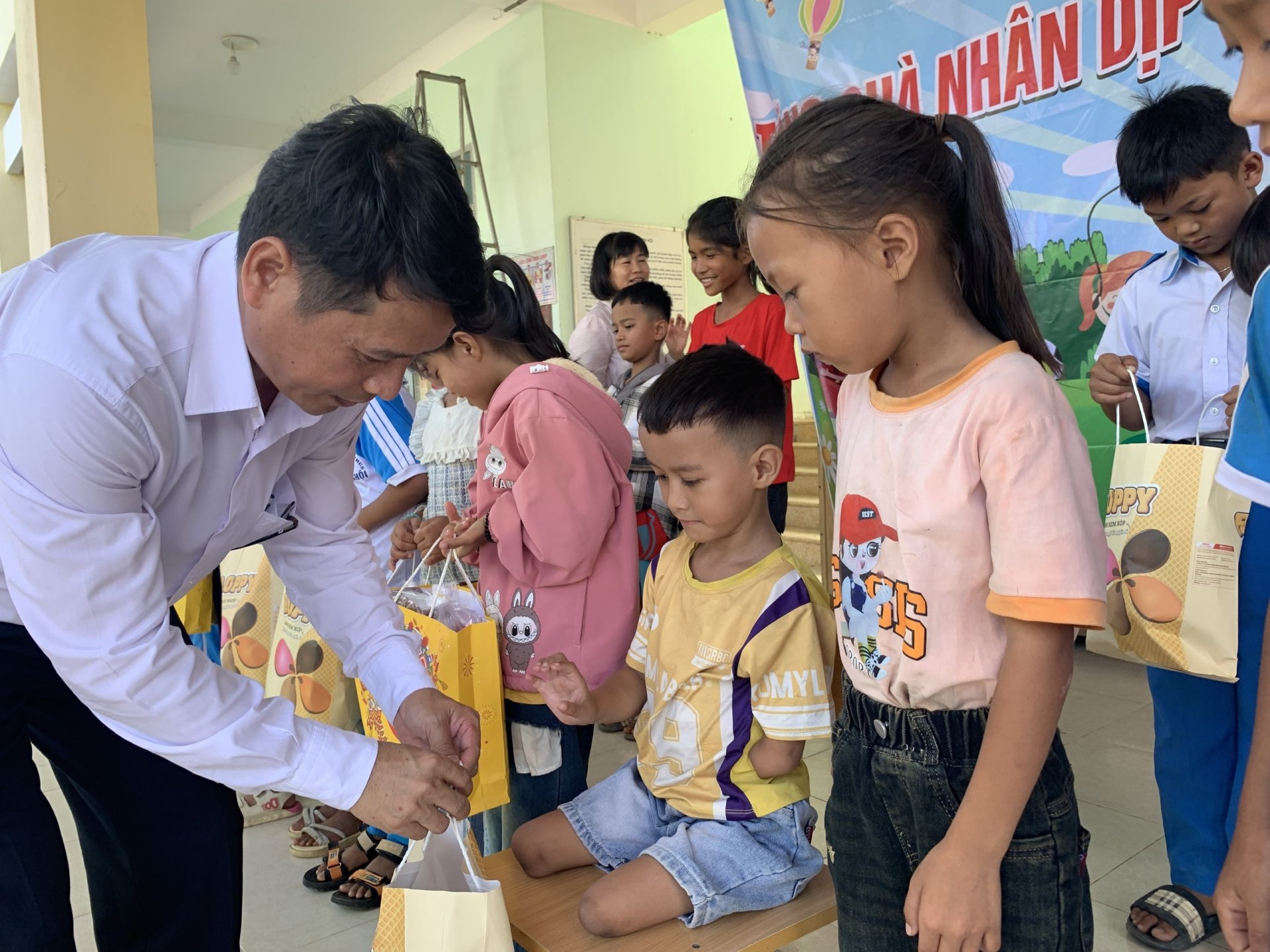 Thầy Dương Lê Toàn, Hiệu trưởng Trường tiểu học 
và THCS xã Sơn Hội (huyện Sơn Hòa) trao quà cho 
trẻ em có hoàn cảnh khó khăn. Ảnh: HOÀNG LÊ