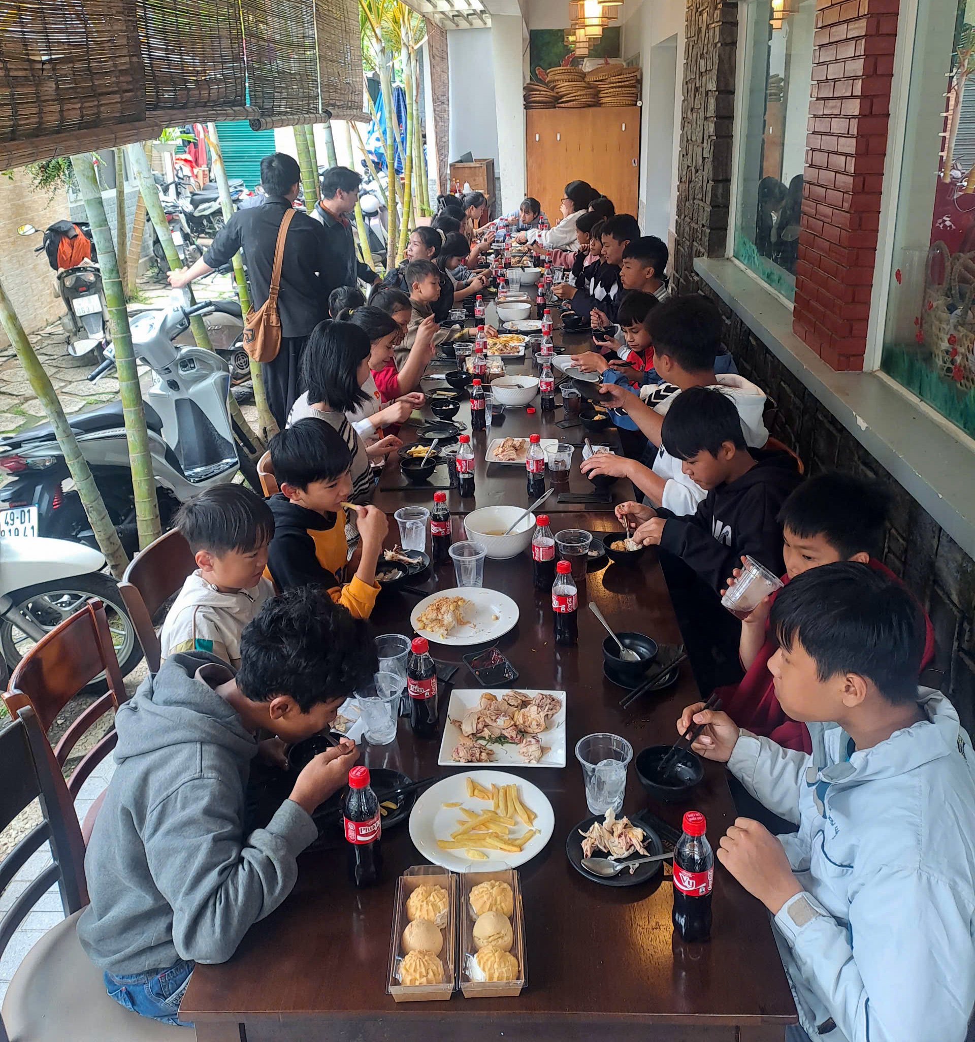 Các em dùng bữa tại nhà hàng và được tình nguyện viên hỗ trợ phục vụ
