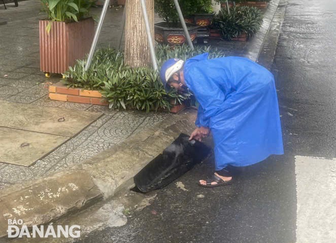 Người dân tại quận Sơn Trà tháo gỡ các tấm che cửa thu nước mưa trước nhà để chống ngập úng. Ảnh: HOÀNG HIỆP