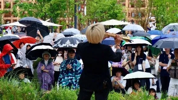 Японская публика, несмотря на дождь, смотрит выступление вьетнамского саксофониста