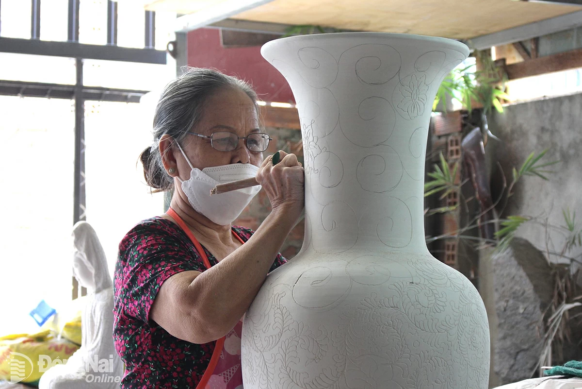 Frau Pham Ngoc Suong (wohnhaft im Bezirk Hoa An, Stadt Bien Hoa) malt fleißig Muster auf Keramikvasen. Foto: L.Na  