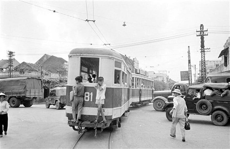 Hai thiếu niên đeo bám sau toa tàu điện bằng gỗ ở trung tâm Hà Nội. Ảnh: Horst Faas / AP Photo. 4/4/1973.