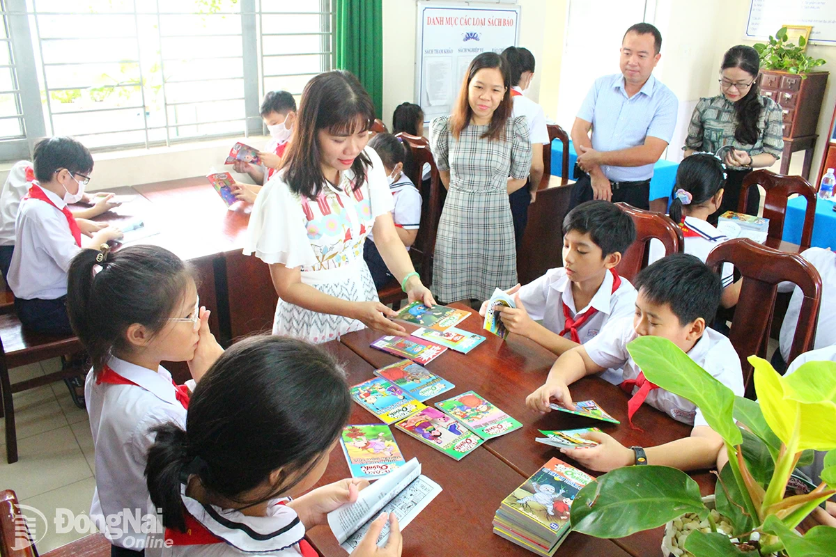 Учитель средней школы для одаренных детей Luong The Vinh Ngo Dinh Van Nhi (в центре) знакомит с книгами учеников начальной школы Ly Thuong Kiet (город Бьенхоа). Фото: L.Na  
