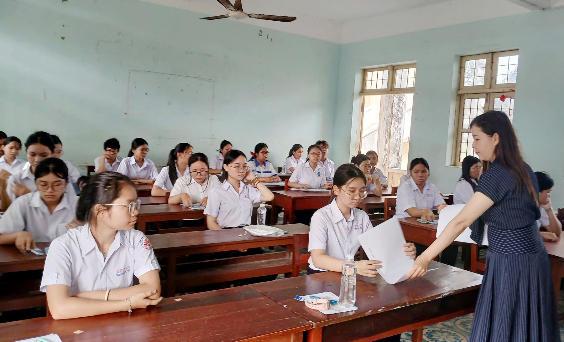 Giám thị coi thi phát giấy nháp cho thí sinh trước khi phát đề thi. Ảnh: TRUNG HIẾU