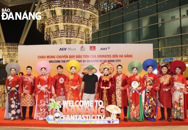 Des touristes prennent des photos souvenirs avec un ao dai vietnamien. Photo : NGOC HA
