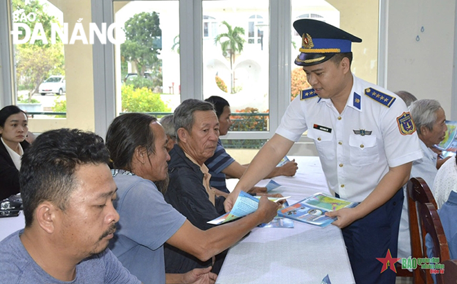 Cán bộ Vùng Cảnh sát biển 2 tuyên truyền, phát tờ rơi cho ngư dân (quận Ngũ Hành Sơn) về việc chống khai thác hải sản bất hợp pháp, không báo cáo, không theo quy định (IUU). Ảnh: P.V