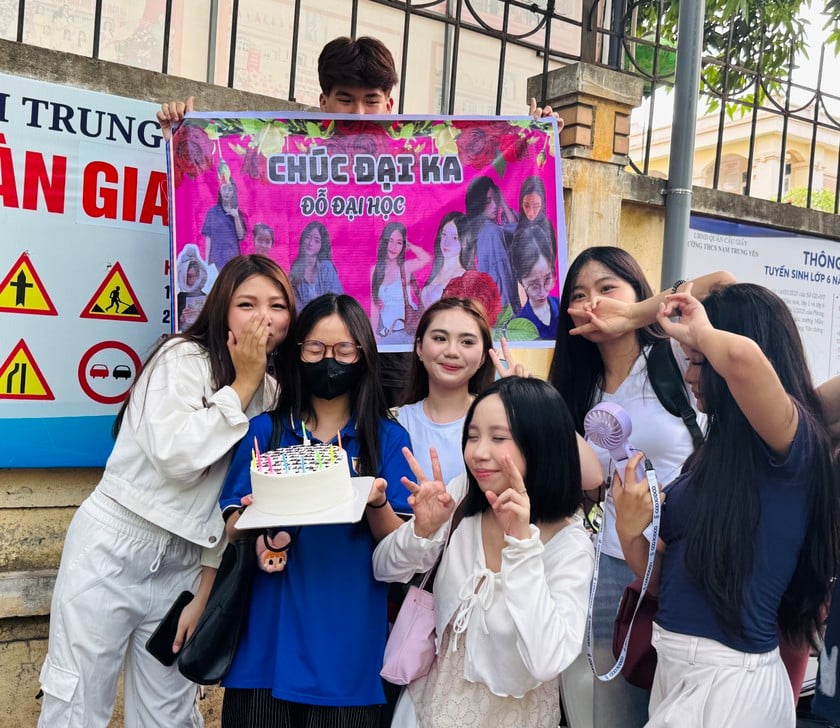 Một thí sinh được bạn mang bánh và khẩu hiệu đi cổ vũ tại điểm thi Trường THCS Nam Trung Yên.