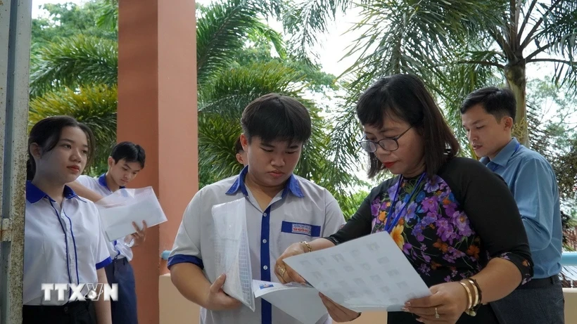เจ้าหน้าที่คุมสอบที่บริเวณสอบโรงเรียนมัธยมฮอนดาต (เกียนซาง) ตรวจสอบข้อมูลของผู้เข้าสอบก่อนเข้าห้องสอบ (ภาพถ่าย: Van Sy/VNA)
