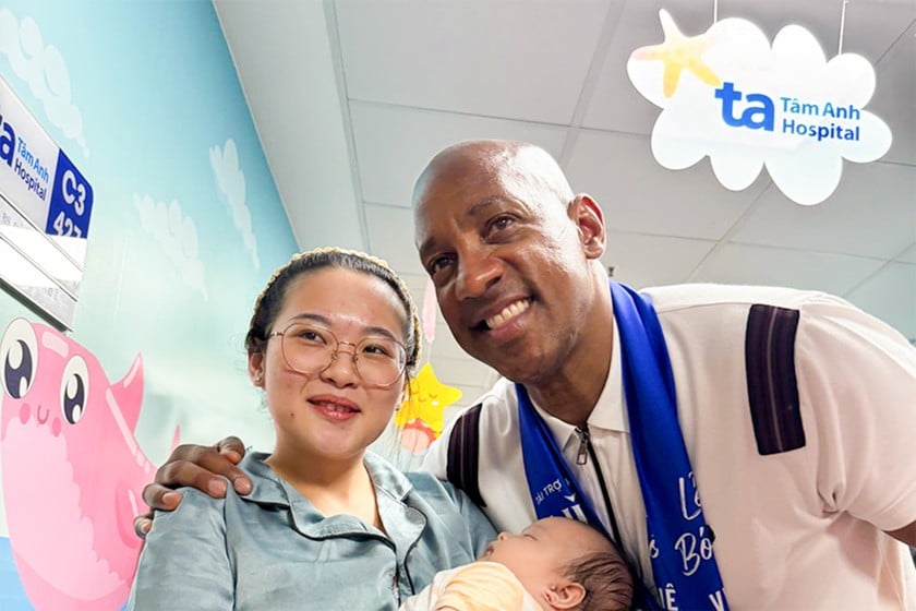 Chị Phạm Tuyết Lan Uyên, mẹ bệnh nhi Đỗ Phạm Bảo Hân bế con chụp hình với thần tượng Dion Dublin. Bố của bé là fan ruột của huyền thoại “Man đỏ” không kịp đến bệnh viện, hai mẹ con đã thay ba xin chụp hình cùng thần tượng. Ảnh: Bệnh viện Đa khoa Tâm Anh.