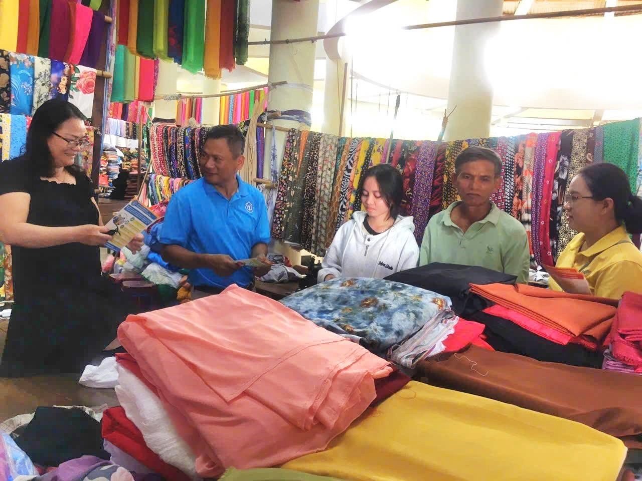 -	Nhân viên BHXH huyện Sông Hinh vận động tiểu thương mua BHXH, BHYT. Ảnh: LỆ VĂN