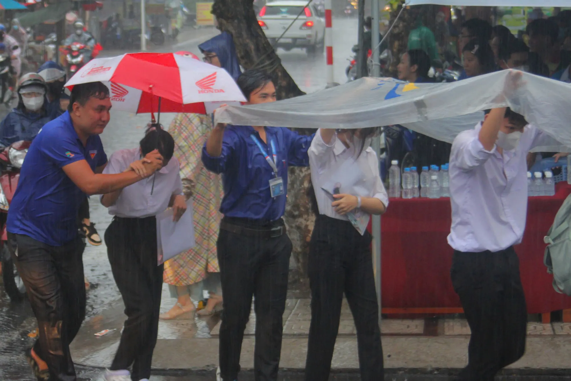 Tình nguyện viên dầm mưa hỗ trợ thí sinh ảnh 1