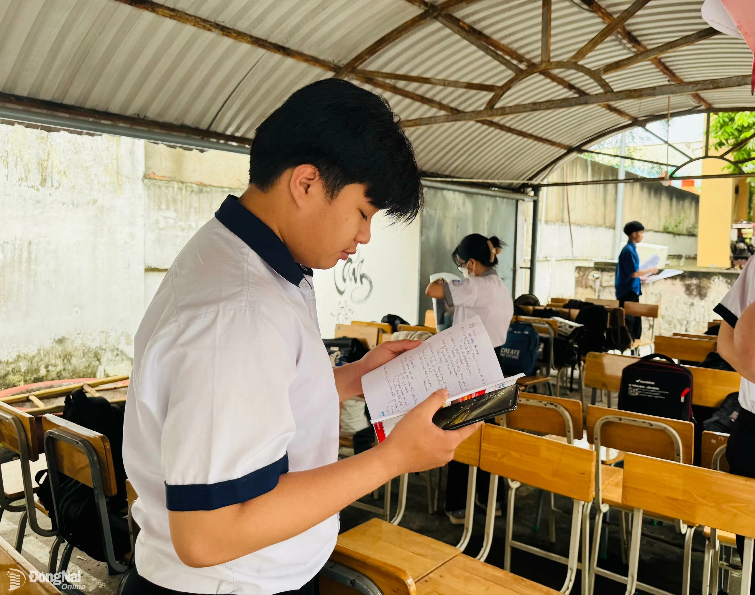Một thí sinh tranh thủ ôn lại kiến thức trước khi vào phòng thi. Ảnh: Hạnh Dung