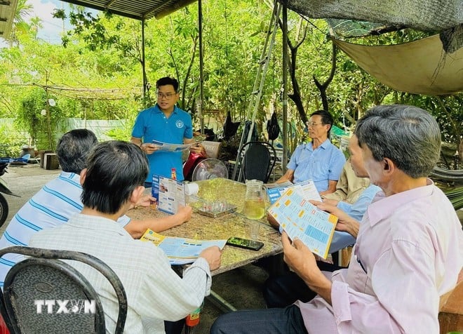 Cán bộ Bảo hiểm Xã hội tỉnh Hậu Giang tuyên truyền chính sách bảo hiểm cho người dân. (Ảnh: TTXVN phát)