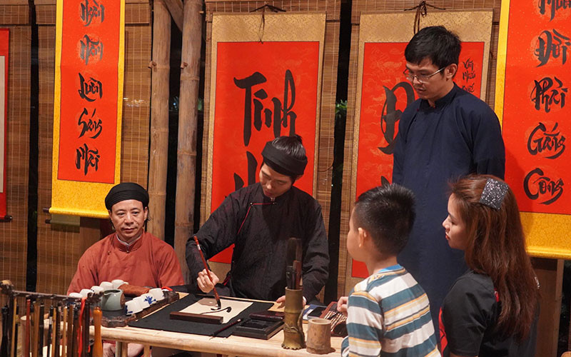 Les touristes demandent de la calligraphie lors de la visite nocturne du Temple de la Littérature - Quoc Tu Giam.