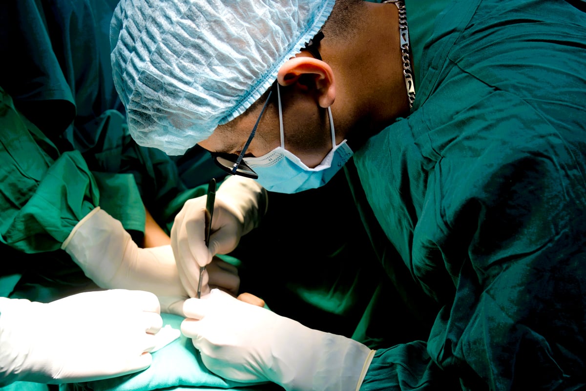 Dưới ánh đèn chiếu rọi, các bác sỹ tập trung cao độ phẫu thuật cho trẻ em bị dị tật.
