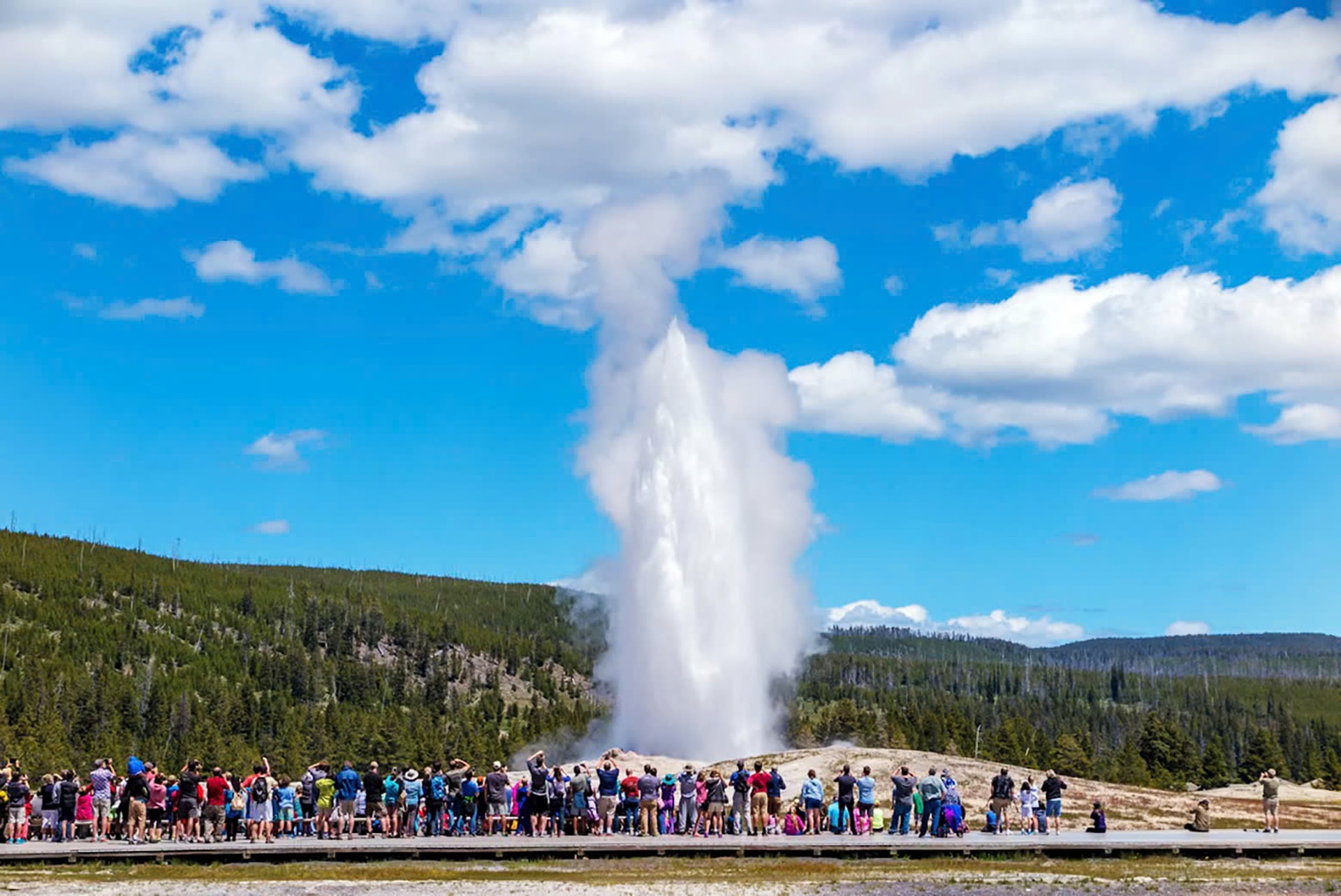 Tourists enjoy the view of the hot springs at old-faithful-generator, the most famous fountain in yellowstone national park.jpg