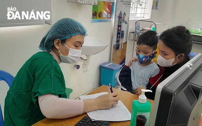 BHXH khu vực XXII chủ động thông tin, tuyên truyền đến người dân về thời điểm ngừng cấp thẻ BHYT giấy và các phương thức sử dụng BHYT điện tử. Trong ảnh: Bác sĩ Bệnh viện Phụ sản - Nhi Đà Nẵng thăm khám và tư vấn sức khỏe cho bệnh nhi. Ảnh: LÊ HÙNG