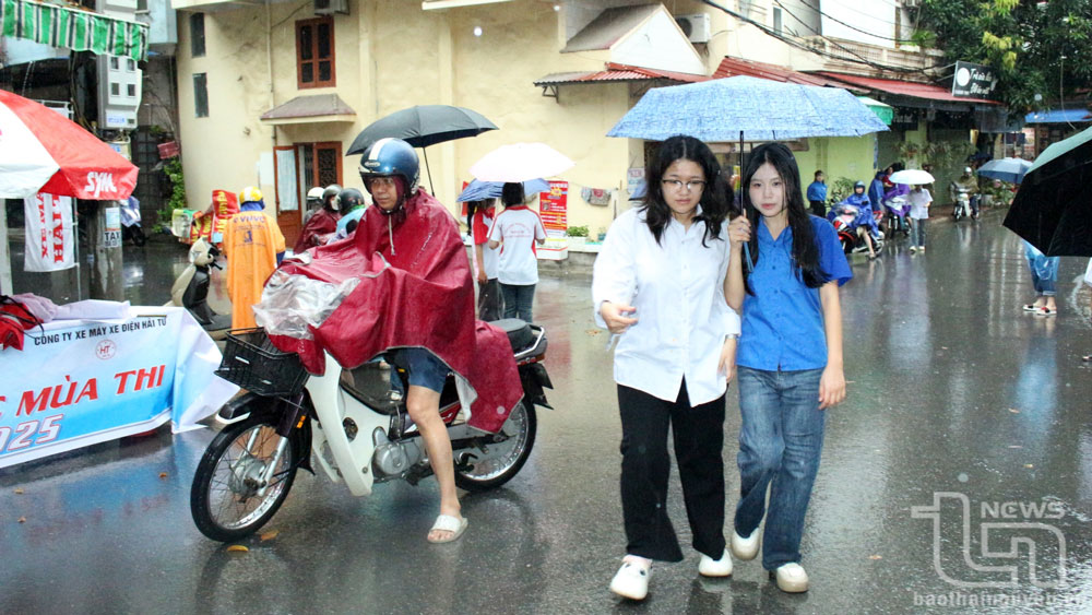 Youth union members and volunteers help hold umbrellas for candidates from the school gate.