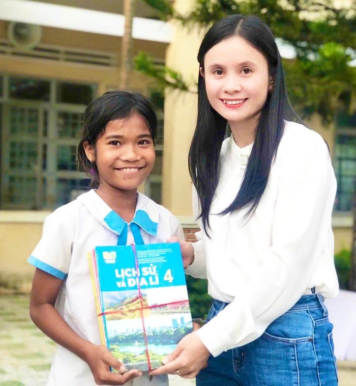 Cô Hoàng Thị Diệu Loan tặng sách giáo khoa cho em Rmah H’Giang, học sinh Trường Tiểu học Phan Chu Trinh (xã Ia Ake, huyện Phú Thiện, Gia Lai)