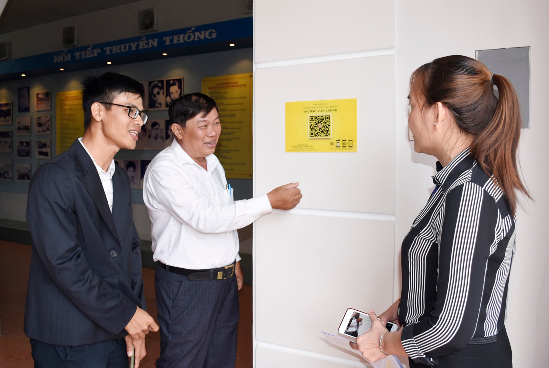 Ông Đỗ Phước Trung, Phó Giám đốc Sở VHTTDL gắn mã QR để truy cập thuyết minh tự động về di tích lịch sử cách mạng Trường Văn Lương.