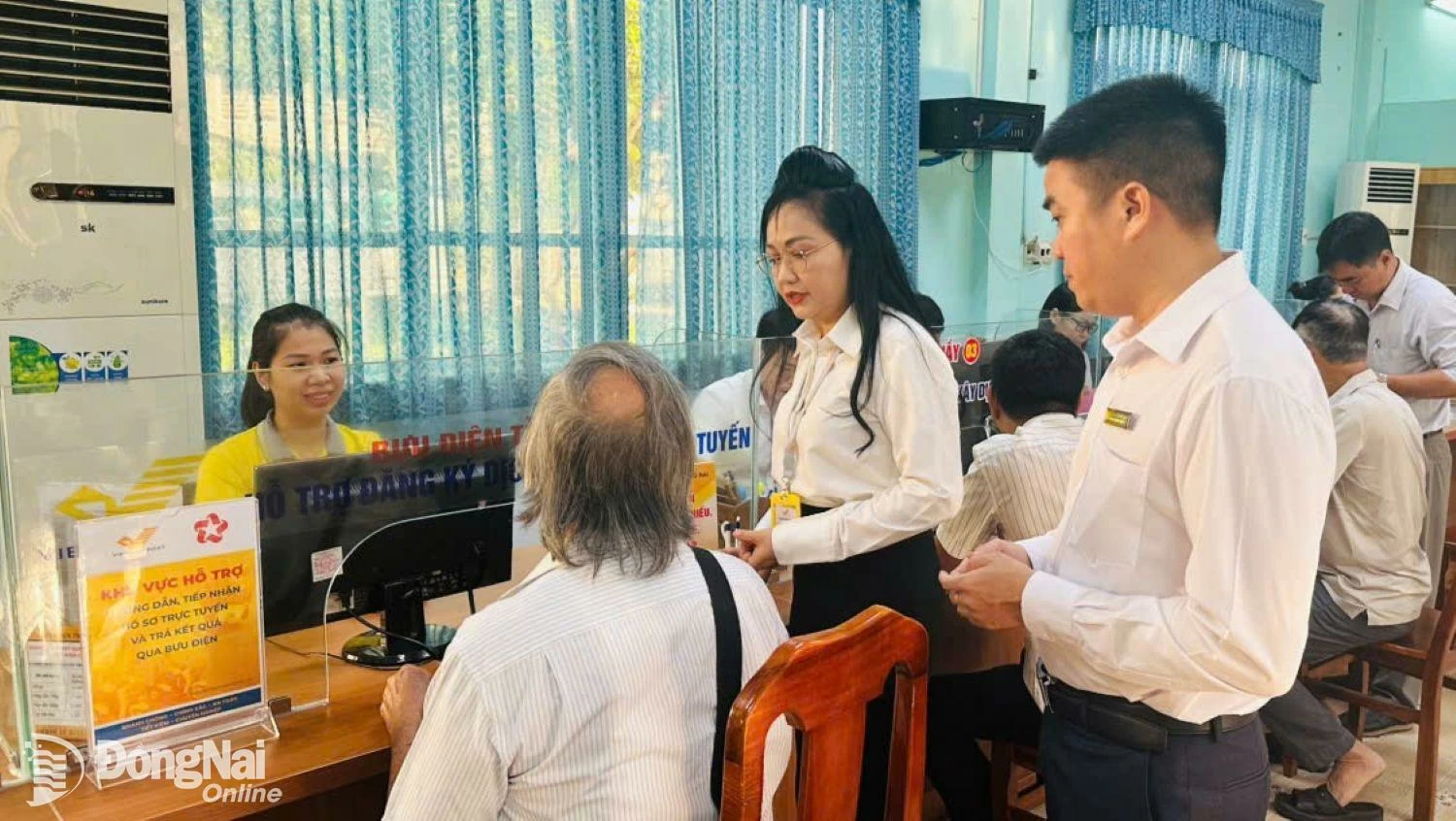 Lãnh đạo Bưu điện tỉnh và phường Trấn Biên hỗ trợ người dân làm thủ tục hành chính trong ngày đầu tiên mô hình chính quyền 2 cấp. Ảnh: Nguyệt Hà