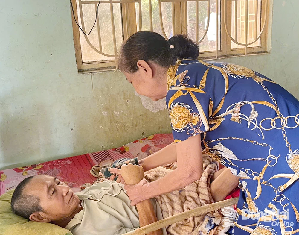 Bà Hoàng chăm sóc chồng bệnh nằm một chỗ. Ảnh: T.Hiền