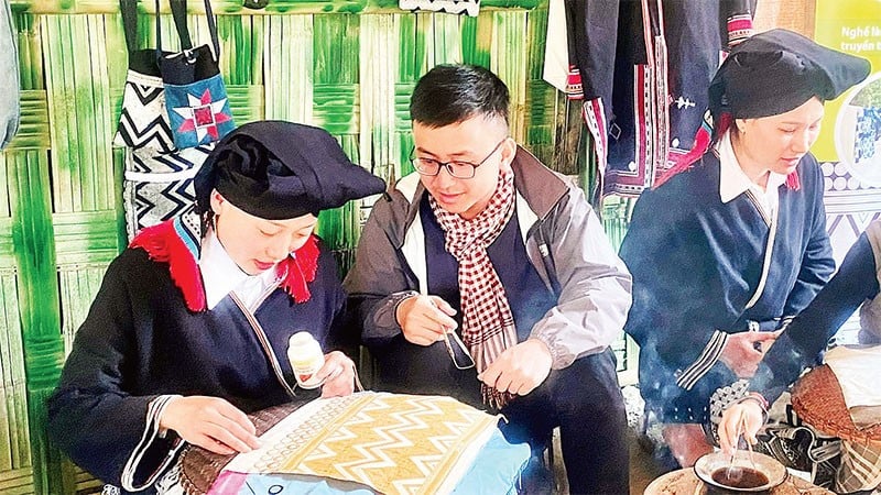 Du khách trải nghiệm nghề truyền thống vẽ sáp ong tại điểm du lịch cộng đồng bản Sưng, xã Cao Sơn.