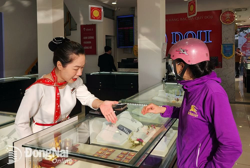 La gente observa lingotes y joyas de oro en un centro de oro, plata y joyería del barrio de Tran Bien. Foto: Hai Quan