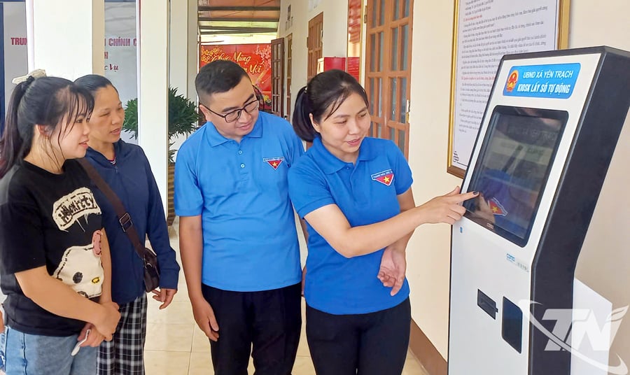 Đoàn viên thanh niên xã Yên Trạch hướng dẫn người dân lấy số thứ tự tại Trung tâm phục vụ hành chính công của xã.
