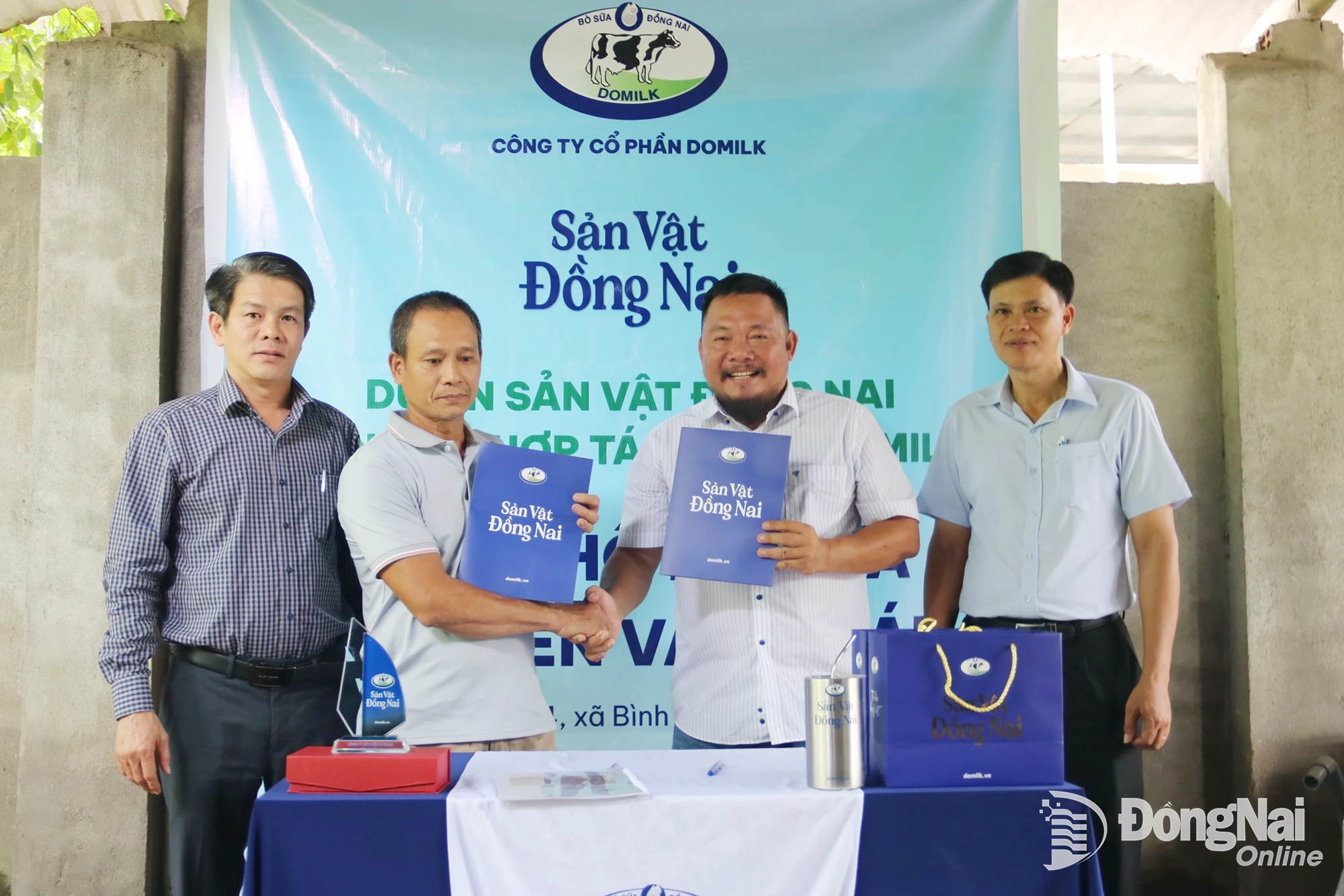 Đại diện Công ty Cổ phần Domilk (bên phải) trao bản ký kết hợp tác với nông hộ Nguyễn Văn Khái (xã Bình An). Ảnh: Vương Thế