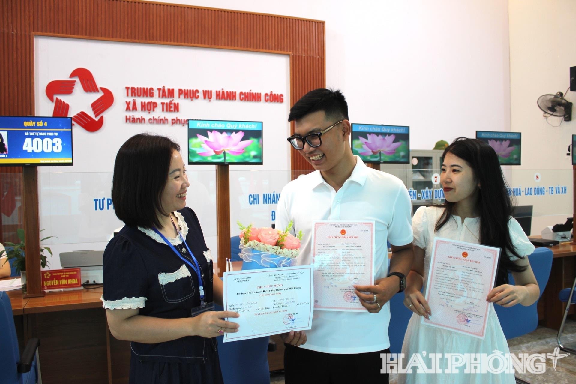 ពេលបំពេញបែបបទ និងត្រូវបានគណៈកម្មាធិការប្រជាជនឃុំហបទៀន បញ្ជាក់ហើយថា ប្តីប្រពន្ធវ័យក្មេងទាំងពីរនាក់នេះបានក្លាយជាប្តីប្រពន្ធជាផ្លូវការ ហើយត្រូវបានប្រគល់សំបុត្រអាពាហ៍ពិពាហ៍យ៉ាងឆាប់រហ័ស ដោយមិនចាំបាច់រង់ចាំយូរ។ នៅឃុំហបទៀន គូស្វាមីភរិយាដែលមកចុះឈ្មោះអាពាហ៍ពិពាហ៍បានទទួលផ្កា និងលិខិតអបអរសាទរពីប្រធានគណៈកម្មាធិការប្រជាជនឃុំ។ ក្នុងរូបថត៖ ថ្នាក់ដឹកនាំគណៈកម្មាធិការប្រជាជនឃុំហបទៀន ជូនកម្រងផ្កា និងលិខិតអបអរសាទរពីប្រធានគណៈកម្មាធិការប្រជាជនឃុំ ជូនដល់គូស្វាមីភរិយាវ័យក្មេងដែលទើបតែបានចុះសំបុត្រអាពាហ៍ពិពាហ៍នៅមជ្ឈមណ្ឌលសេវារដ្ឋបាលសាធារណៈ។