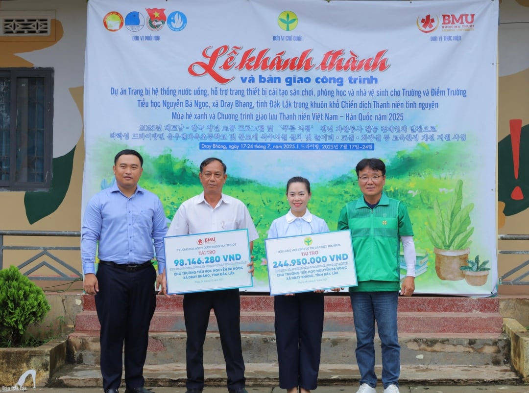 Đại diện Hội Làng mới tỉnh Jeonbuk, Hàn Quốc và Trường Đại học Y Dược Buôn Ma Thuột trao bảng tượng trưng kinh phí hỗ trợ thực hiện các công trình cho Trường Tiểu học Nguyễn Bá Ngọc. 