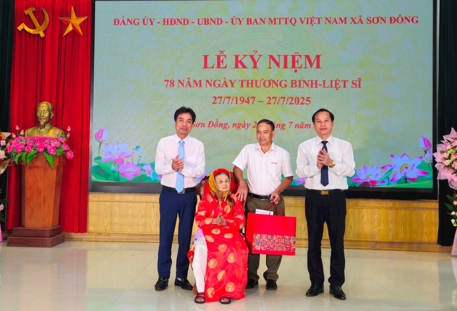 Phó Bí thư Thường trực Đảng ủy xã Sơn Đồng Nguyễn Đăng Sơn và Phó Bí thư Đảng ủy, Chủ tịch UBND xã Sơn Đồng Phạm Gia Lộc trao quà tặng Bà mẹ Việt Nam Anh hùng Nguyễn Thị Lân. Ảnh: Ánh Dương 