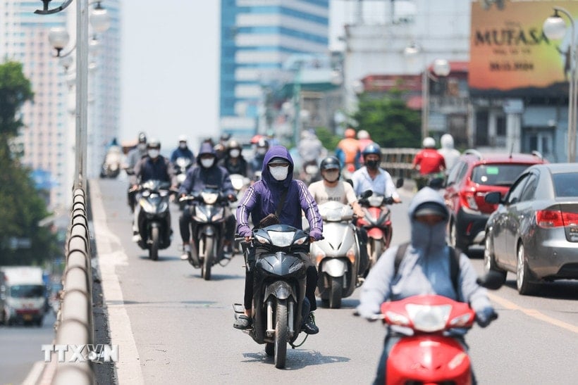 더운 날씨에 교통 체증에 시달릴 때 마스크와 자외선 차단 의류는 필수품입니다. (사진: 르 동/VNA)