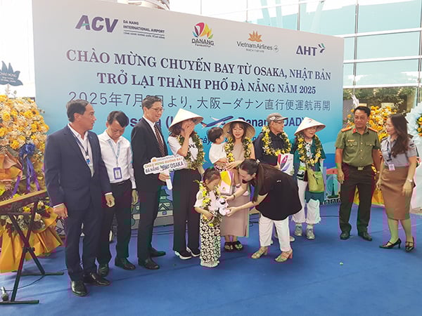 Phó Giám đốc Sở VHTT&DL Đà Nẵng Nguyễn Thị Hoài An tặng quà chúc mừng các vị khách đầu tiên trên chuyến bay VN337 hạ cánh sân bay Đà Nẵng trưa ngày 3/7.