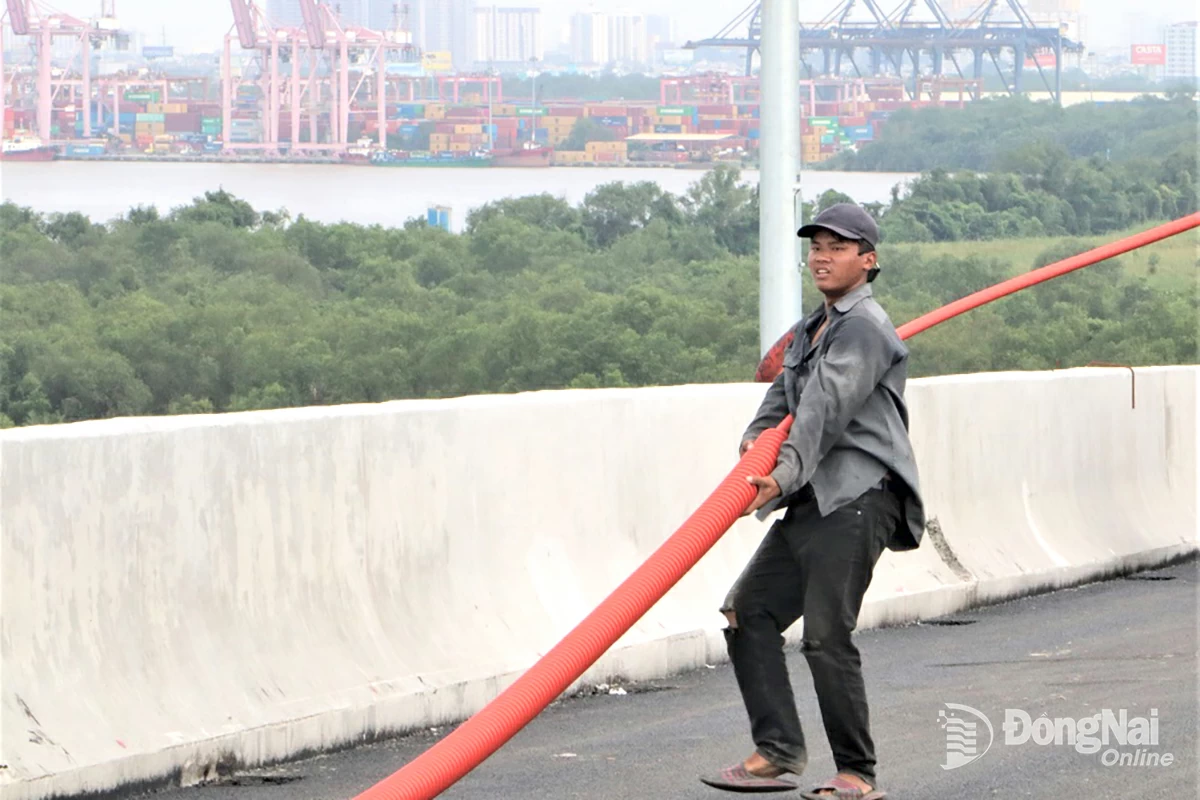 Những ngày này, các công nhân đang hối hả thi công hoàn thiện những hạng mục cuối, trong đó có hạng mục đấu nối hệ thống điện chiếu sáng trên cầu Nhơn Trạch. Ảnh: Phạm Tùng