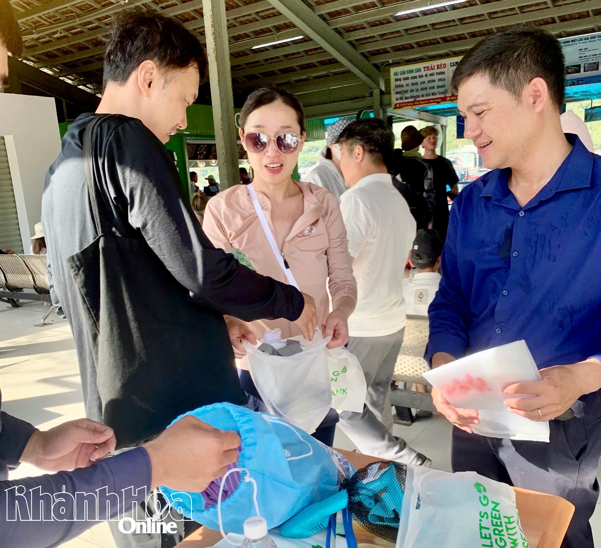 Thành viên Ban Quản lý vịnh Nha Trang phát túi phân hủy sinh học để thay thế túi ni lông khó phân hủy cho du khách khi qua bến tàu.