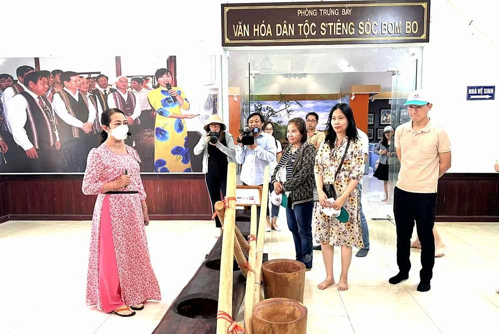 Du khách trải nghiệm tiếng đàn đá, một nhạc cụ được trưng bày tại Địa điểm ghi dấu Phong trào Giã gạo nuôi quân tại sóc Bom Bo, xã Bom Bo. Ảnh: N.Liên