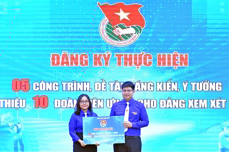 Bí thư Đoàn Thanh niên Báo Nhân Dân Lê Khánh Bình (bên trái) trao biển đăng ký thực hiện các công trình thanh niên hưởng ứng đợt thi đua.