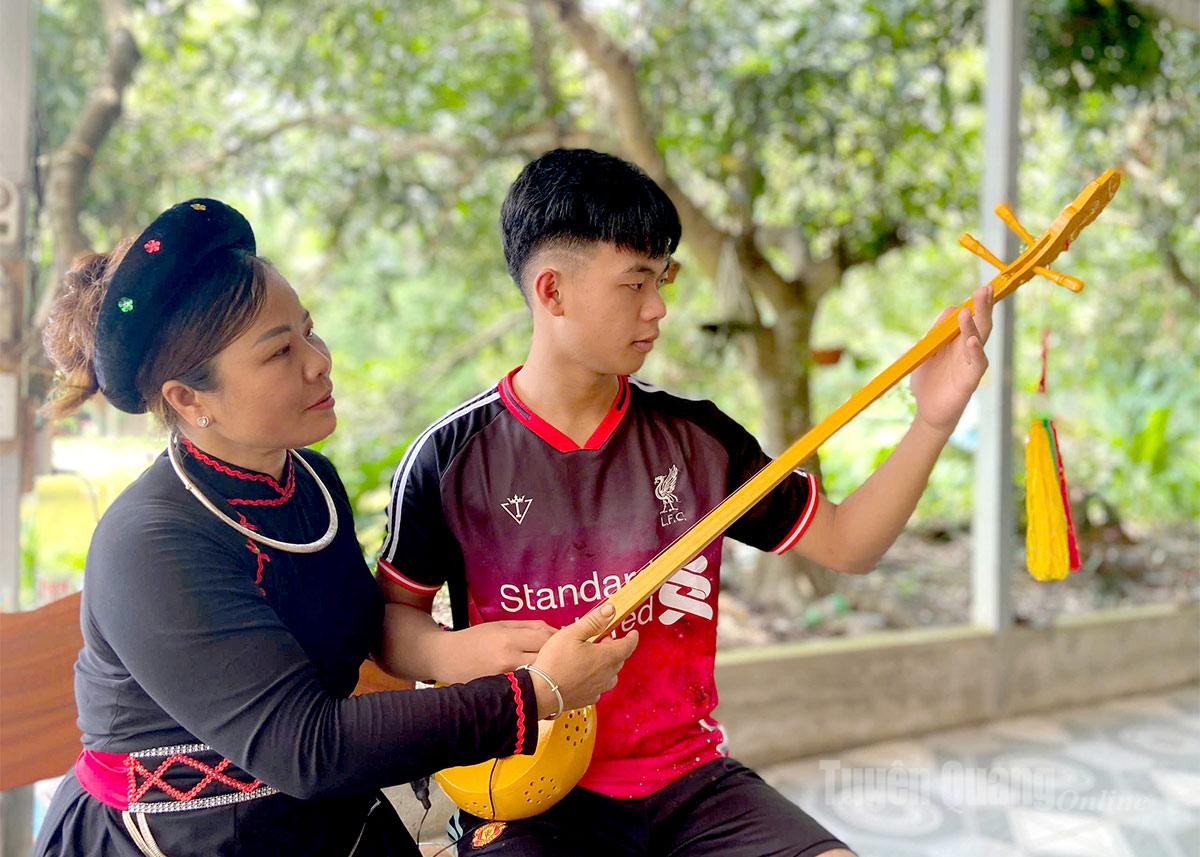Chị Bàn Thị Lương hướng dẫn con trai đánh đàn Tính.