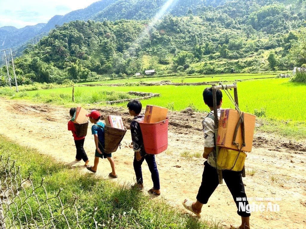 Trẻ em người Mông ở bản Huồi Mới cõng hàng nhu yếu phẩm của đoàn thiện nguyện trao tặngvượt núi về bản, mất khoảng 10 tiếng đồng hồ đi bộ do đường sạt lở, chia cắt nghiêm trọng. Ảnh: Văn Trường.