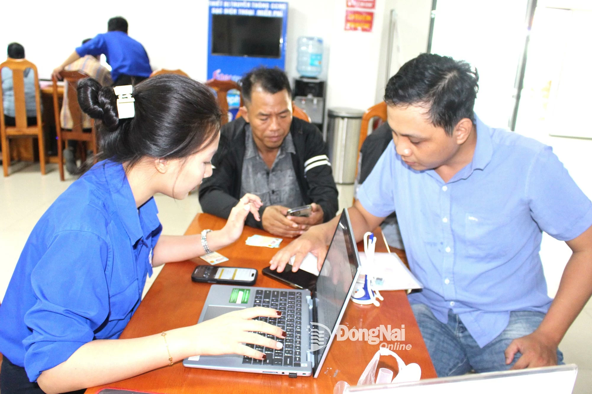 Les membres de l'Union des jeunes du Centre de services administratifs de la commune de Long Thanh guident les personnes souhaitant déposer leur candidature en ligne. Photo : H. Thao