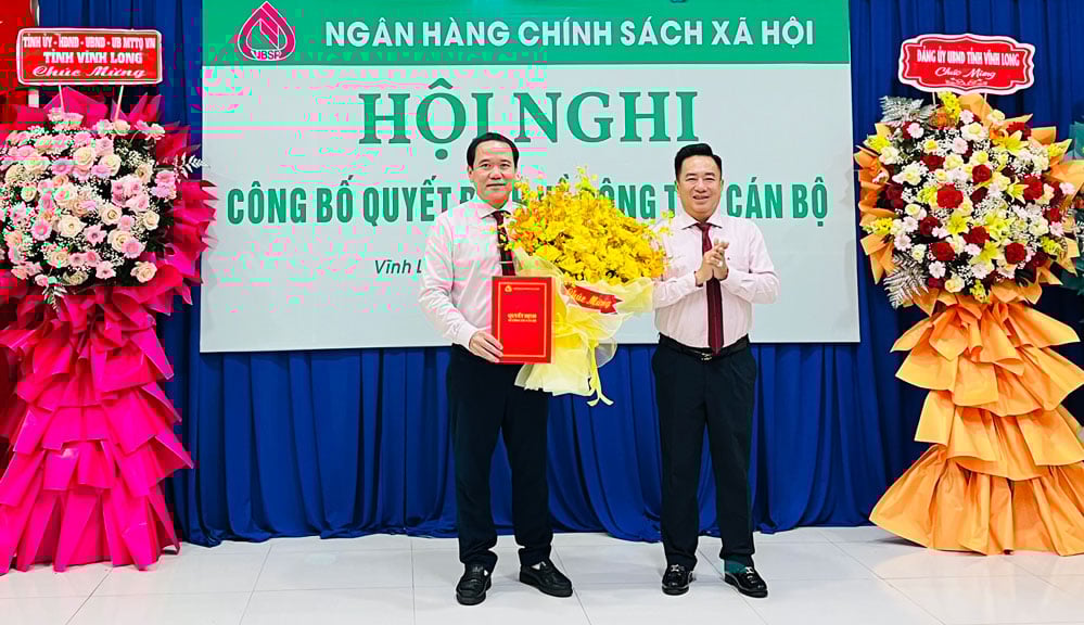 Ông Huỳnh Văn Thuận - Phó Tổng Giám đốc NHCSXH trao quyết định bổ nhiệm ông Lê Hoàng Phi (bên trái) làm Giám đốc chi nhánh NHCSXH tỉnh Vĩnh Long.