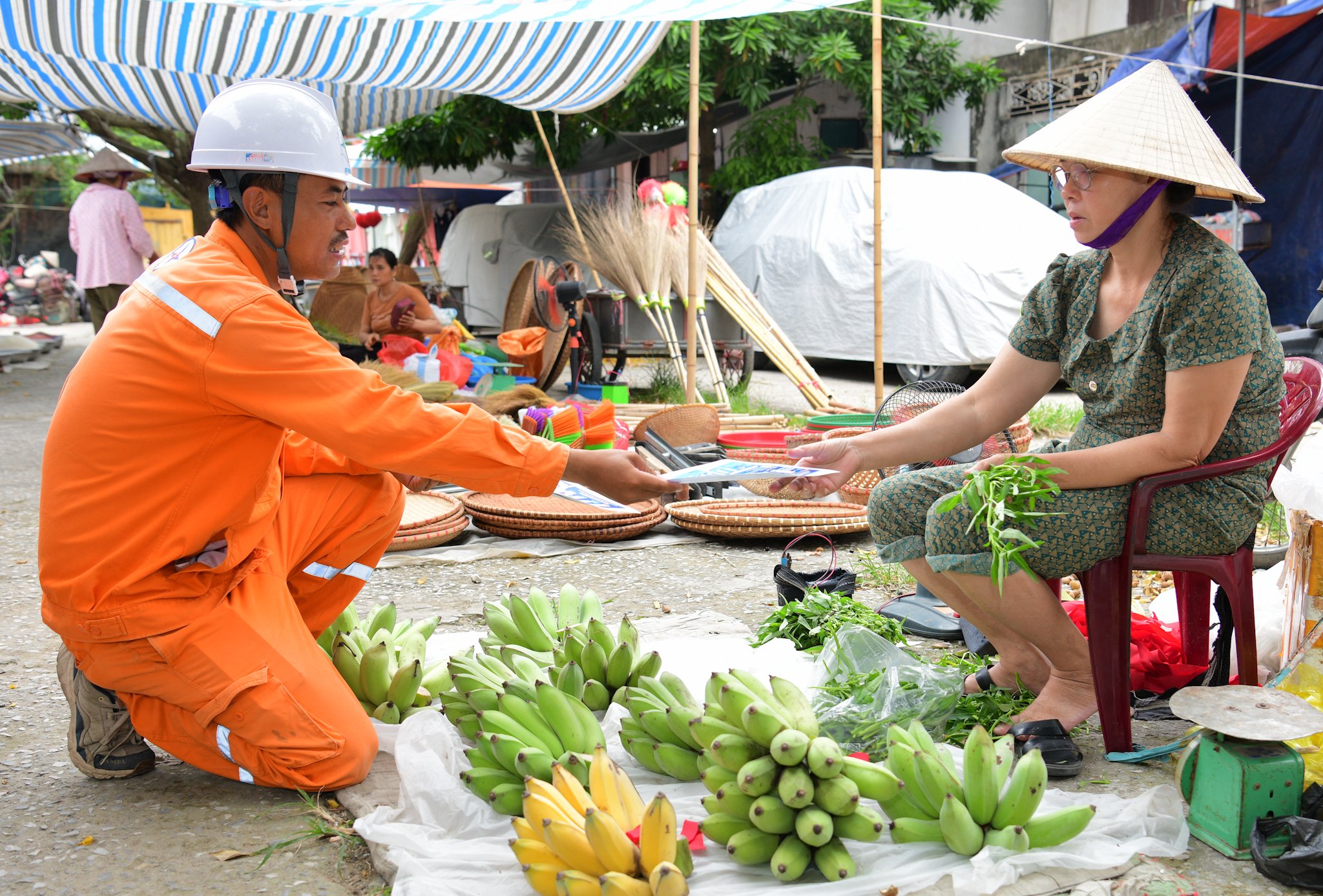 Nhân viên Công ty Điện lực Ninh Bình phát tờ rơi hướng dẫn khách hàng các phương thức thanh toán tiền điện mới. Ảnh: Trường Giang